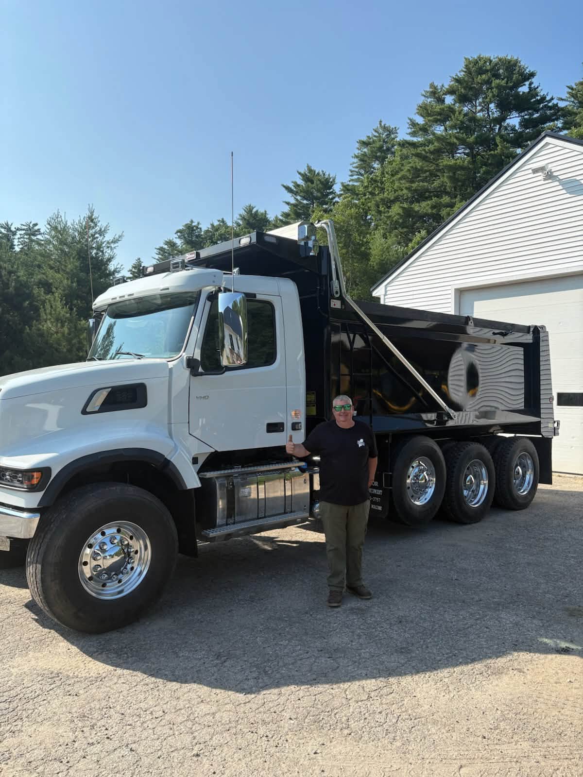 A member of the 207 Excavation team giving a thumbs up beside a new dump truck